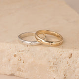 Two gold rings on a textured beige surface