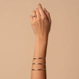 Hand wearing a ring and gold bangles with a beige background