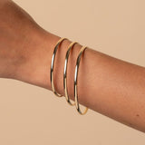 Hand wearing gold bracelets on a beige background